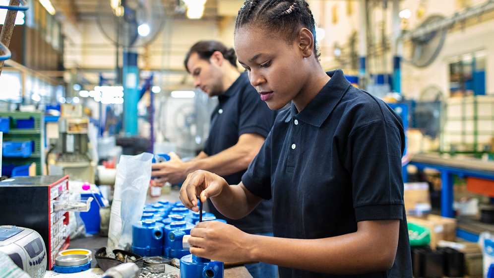 Two workers assemble items in a factory.