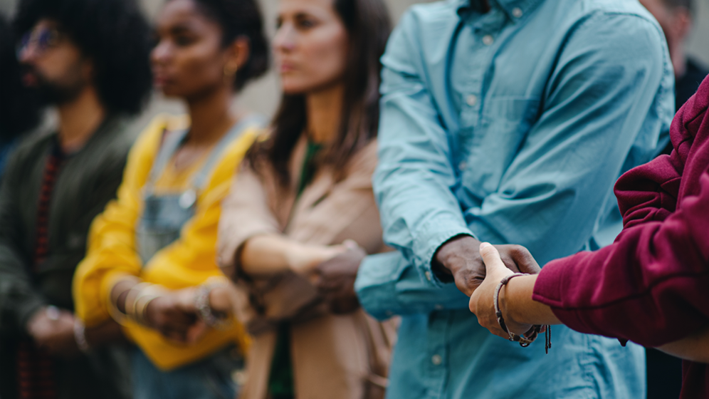 Diverse group of people in a line holding hands. 