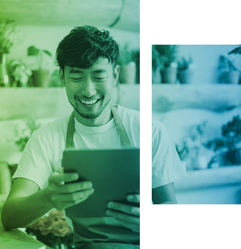 A florist in his flower shop smiles as he looks at his tablet screen. 