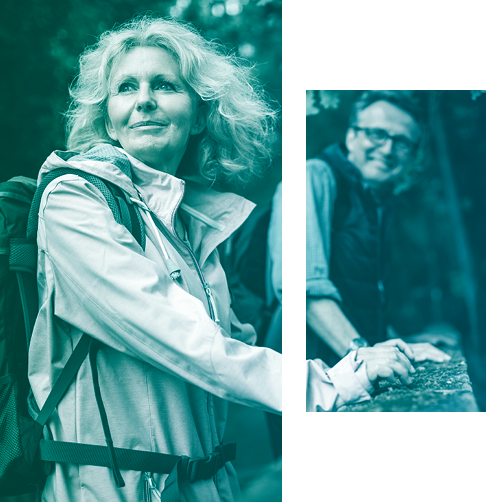 Woman and man dressed in outdoor gear, enjoying a hike in the woods.