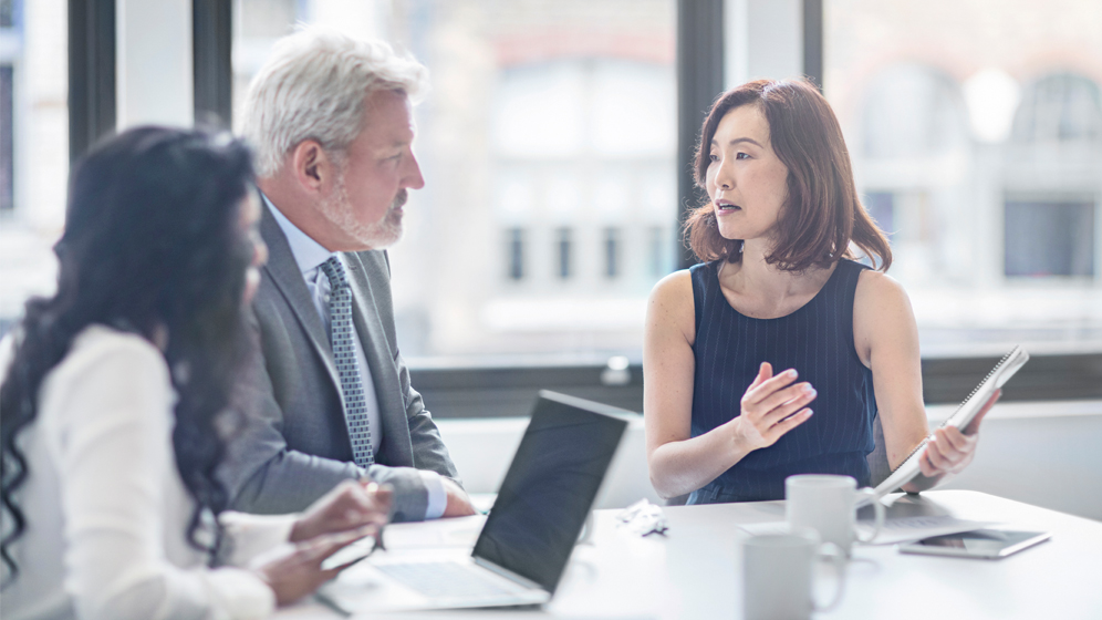 An advisor discusses financial matters with clients in a boardroom. 